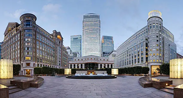 Wide angle panoramic view of the three tallest skyscrapers of the Canary Wharf skyline as viewed from Cabot Square, London
