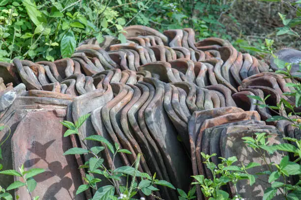 pile of unused clay tiles, rooftile. a component of the roof covering the upper surface of a building consisting of parts arranged overlapping one another