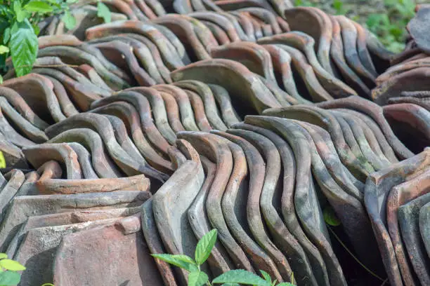 pile of unused clay tiles, rooftile. a component of the roof covering the upper surface of a building consisting of parts arranged overlapping one another