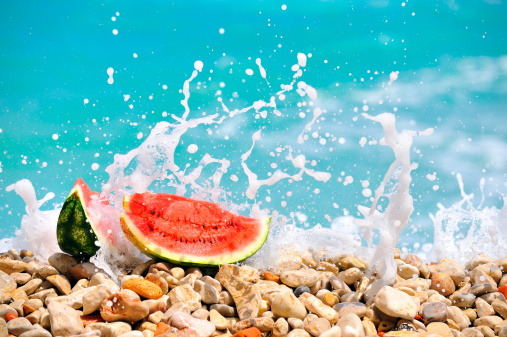slices of watermelon on the seashore and a wave breaking