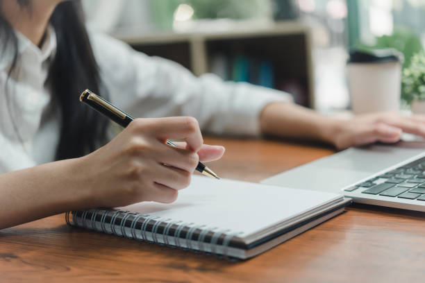 istock Woman hand with notebook for planning with laptop computer and documents.Freelance career, information and strategy and journal report. 1472422660
