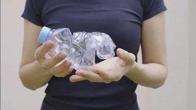 A woman crushing a plastic bottle with her hands