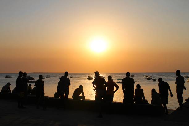 istock Young men watch the sun set from the beach 1472428482