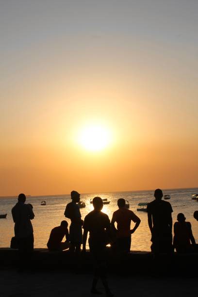 istock Young men watch the sun set from the beach 1472428484