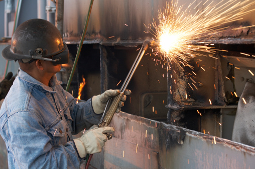 a welder working a torch at shipyard