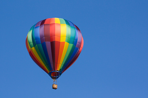 A multicolored hot air balloon floats in the blue sky