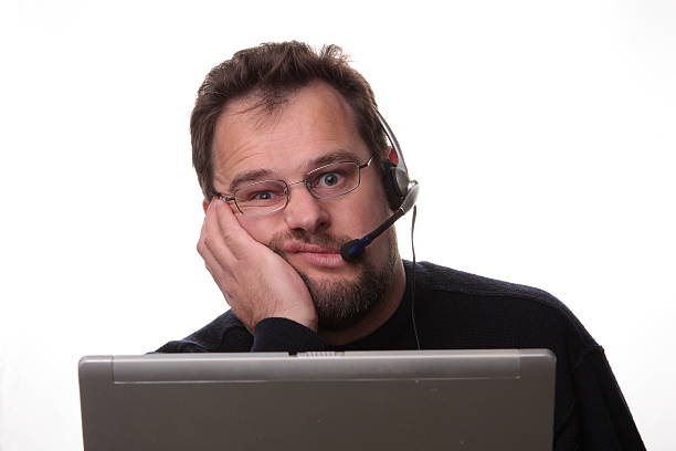 uomo annoiato guardando computer operatore - frustration telephone computer it support foto e immagini stock