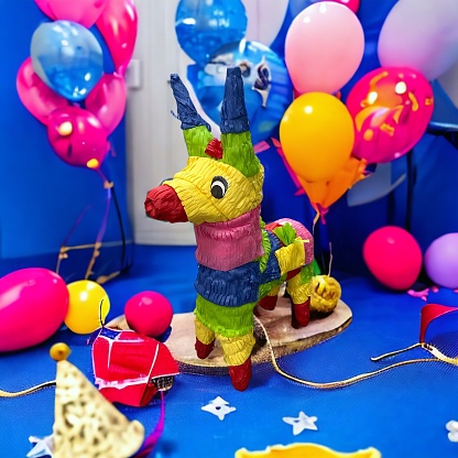 A head and shoulders image of an adult clown making balloon animals as an entertainment trick.