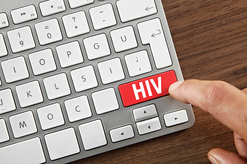 Man pushing ”HIV” key on computer keyboard.