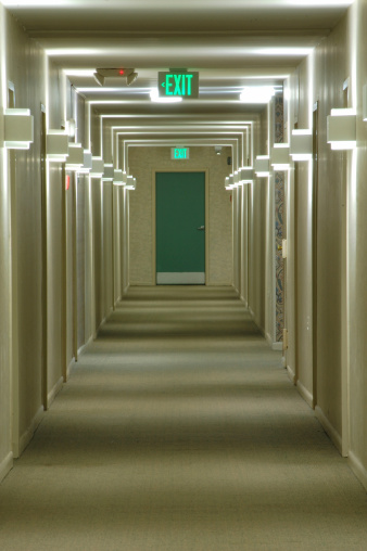 Emergency exit at the end of a long corridor in an apartment complex.