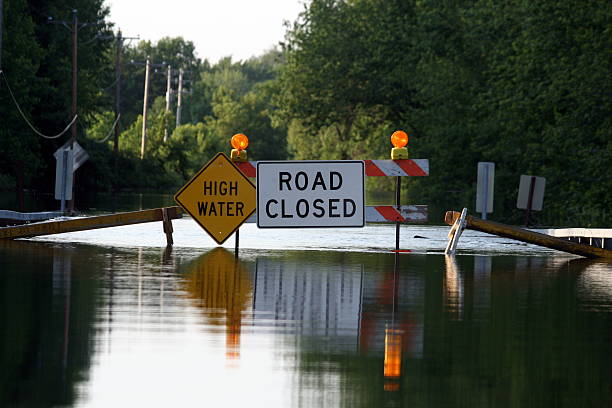 A road closure signage as water covers the road A road closed due to flooding. natural disaster photos stock pictures, royalty-free photos & images