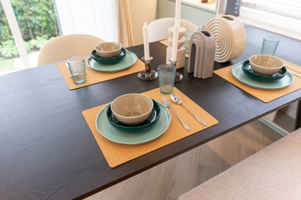 istock Modern dining room with wooden table and green plate setting on table. 1472438990