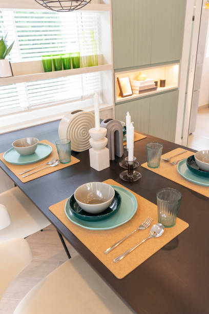 istock Modern dining room with wooden table and green plate setting on table. 1472438991