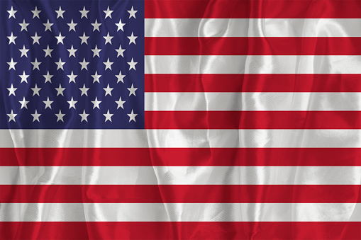 The flag of the United States of America on a silk background is a great national symbol. Texture of fabrics The official state symbol of the country