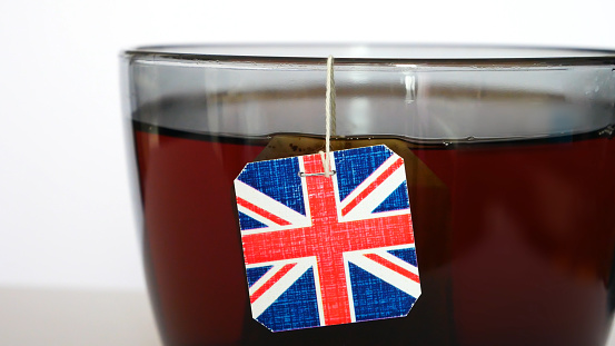 A big cup of tea brewing with a tea bag with a Union Jack tag close-up