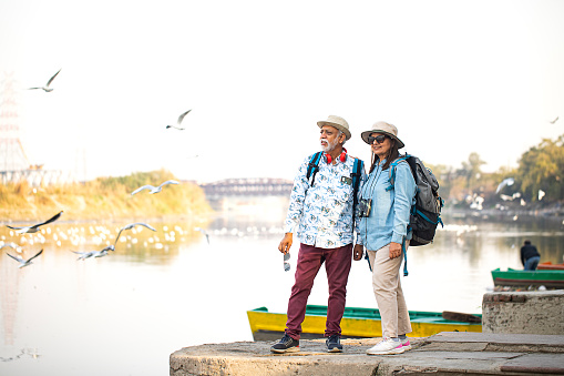 Senior couple tourist admiring view standing on concrete platform by lake