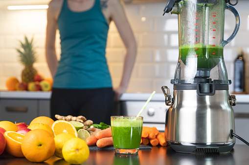 Young women preparing a vegetarian healthy smoothie for detox and preparing for sport exercise.