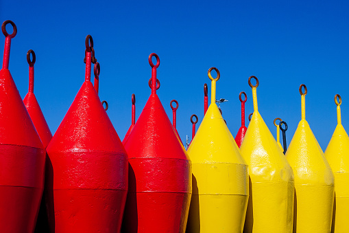 Red and yellow buoys at land of Terschelling. A buoy is a floating device that can have many purposes. It can be anchored (stationary) or allowed to drift with ocean currents.