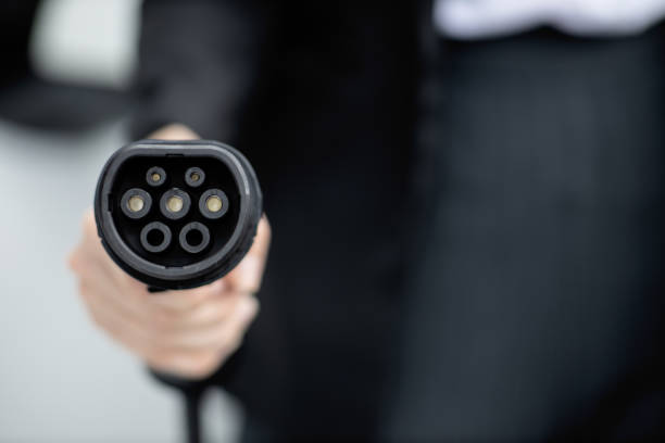 istock Focus closeup hand pointing EV plug for electric vehicle as progressive idea. 1472451529