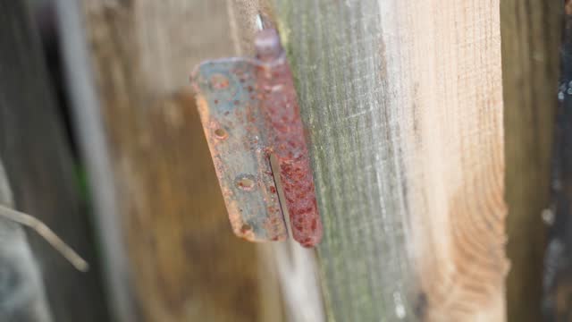 Old rusty door hinge on a wooden beam close-up, smooth camera movement