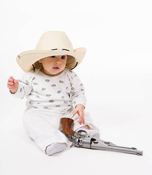Little cowboy Little boy in a cowboy hat with a revolver on a white background baby gun stock pictures, royalty-free photos & images