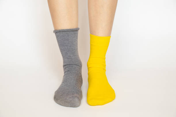 piernas de mujer en calcetín diferente, una azul y la otra amarilla sobre fondo blanco - sock wool multi colored isolated fotografías e imágenes de stock