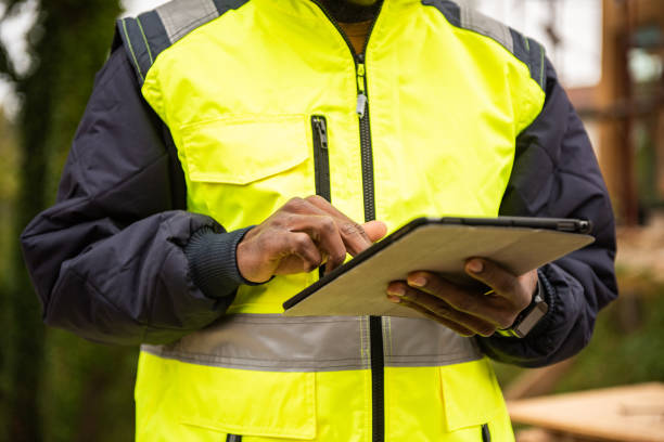 istock Contractor in protective waistcoat using tablet close up 1472461028