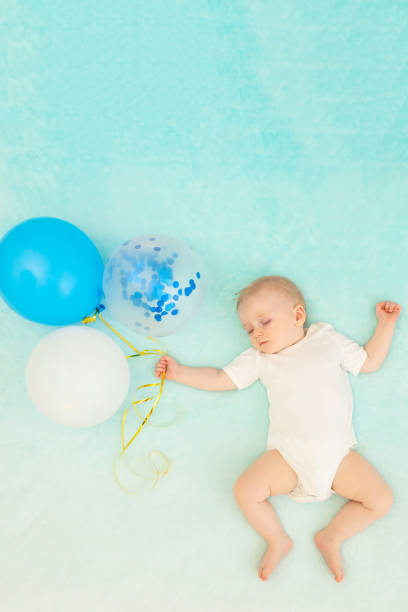 istock a baby boy on a blue background is sleeping and in a dream flying with balloons, space for text 1472464607