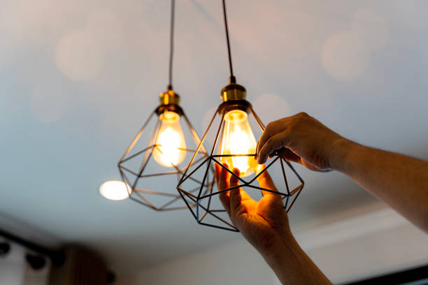 Decorative antique edison style filament light bulbs hanging. An electrician is installing spotlights on the ceiling Electric LED Lightbulb Change In Light At Home. Decorative antique edison style filament light bulbs hanging. An electrician is installing spotlights on the ceiling led lighting interior stock pictures, royalty-free photos & images