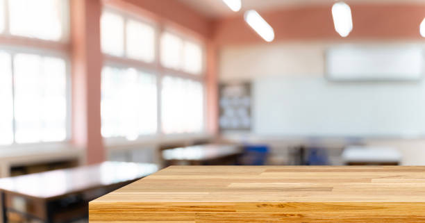 Cropped shot of wooden table and copy space in blurred study room.Empty classroom or presentation room interior with desks stock photo