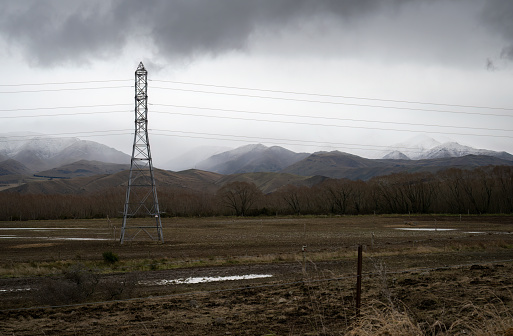 High voltage power pylon and powerlines. Snow-capped mountains in the background. Canterbury, South Island