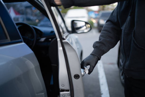 primer plano de un ladrón con una camisa negra y guantes negros. trató de abrir la puerta del auto y trató de entrar. concepto de robo de coches. - ladrón fotografías e imágenes de stock