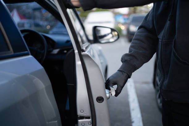Close-up shot of a thief wearing a black shirt and black gloves. He tried to open the car door and tried to break in. car theft concept. Close-up shot of a thief wearing a black shirt and black gloves. He tried to open the car door and tried to break in. car theft concept. thief stock pictures, royalty-free photos & images