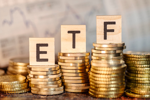 Several stacks with coins and the term ETF and a chart with stock prices.