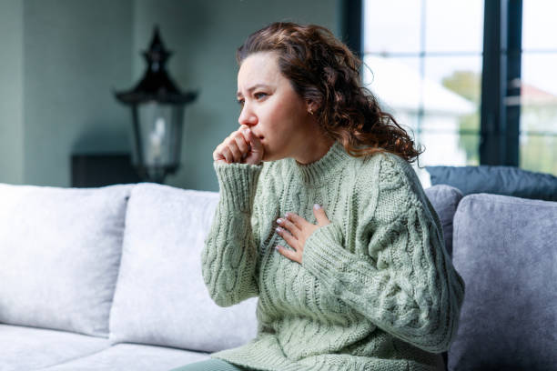 istock Sick woman sitting on sofa and having cough 1472468361