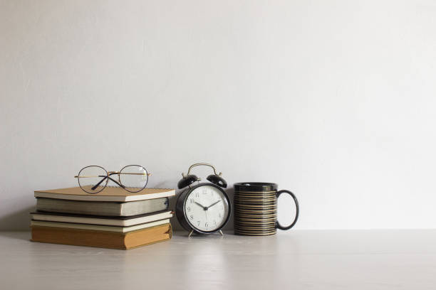 istock Reading concept with reading glasses, clock and coffee cups with light. 1472469350