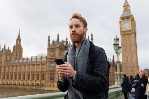 Serious bearded man with smartphone on London street