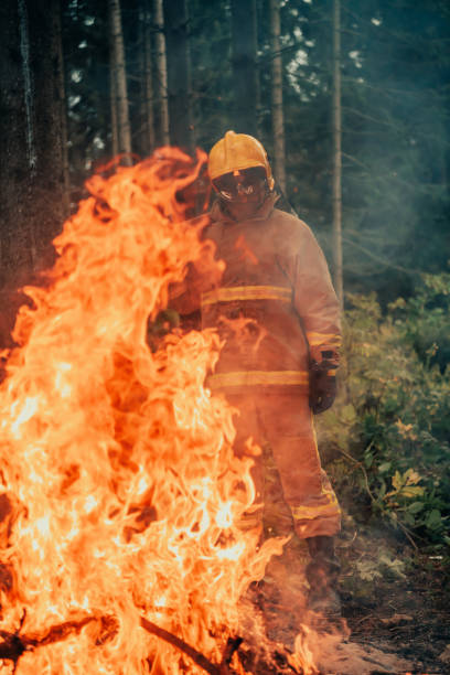 istock Firefighter at job. Firefighter in dangerous forest areas surrounded by strong fire. Concept of the work of the fire service 1472470037