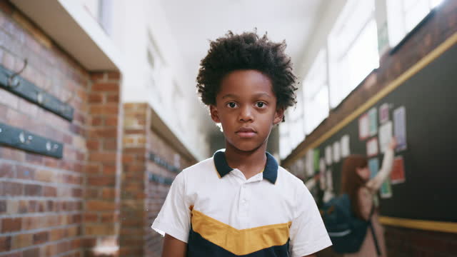 Serious boy, portrait and face in school corridor for bullying awareness, children mental health or social anxiety. Sad black child, kid and student in hallway with learning, education or studying