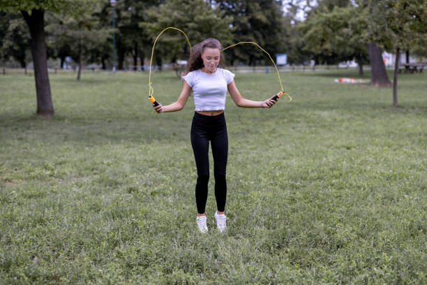 Fit young Caucasian woman warming up her muscles with a jumping rope in the forest