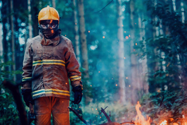 istock Firefighter at job. Firefighter in dangerous forest areas surrounded by strong fire. Concept of the work of the fire service 1472473204