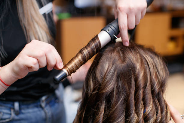istock Using hot curler and making curls in hair salon 1472473800