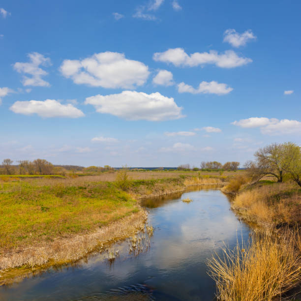 istock calm river flow among prairie under blue cloudy sky 1472474086