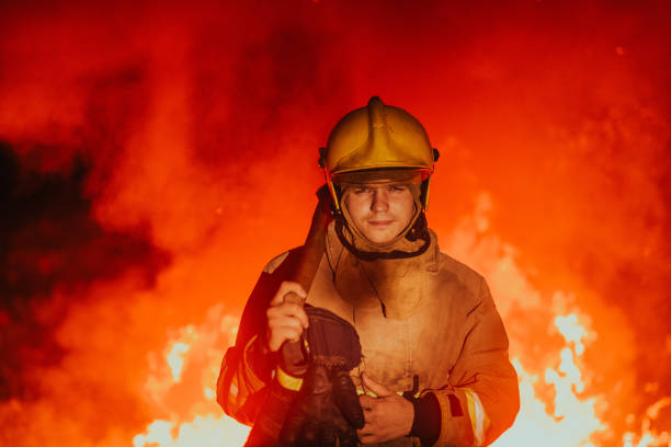 istock Firefighter at job. Firefighter in dangerous forest areas surrounded by strong fire. Concept of the work of the fire service 1472474444