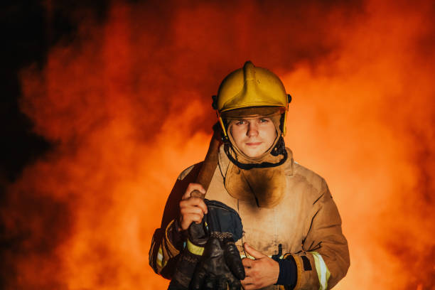 istock Firefighter at job. Firefighter in dangerous forest areas surrounded by strong fire. Concept of the work of the fire service 1472474511