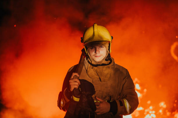 istock Firefighter at job. Firefighter in dangerous forest areas surrounded by strong fire. Concept of the work of the fire service 1472475120