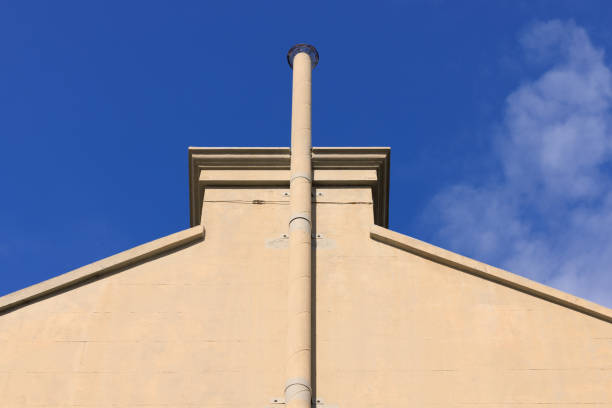 Close-up on a side wall of a building with chimney and deep blue sky beyond.