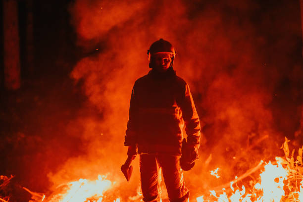 istock Firefighter at job. Firefighter in dangerous forest areas surrounded by strong fire. Concept of the work of the fire service 1472475324