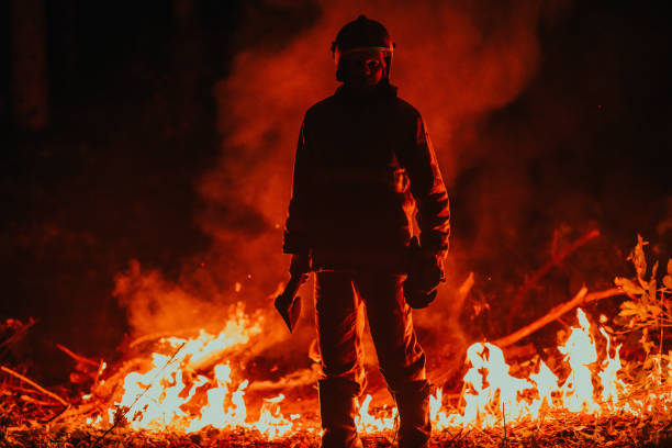 istock Firefighter at job. Firefighter in dangerous forest areas surrounded by strong fire. Concept of the work of the fire service 1472475366