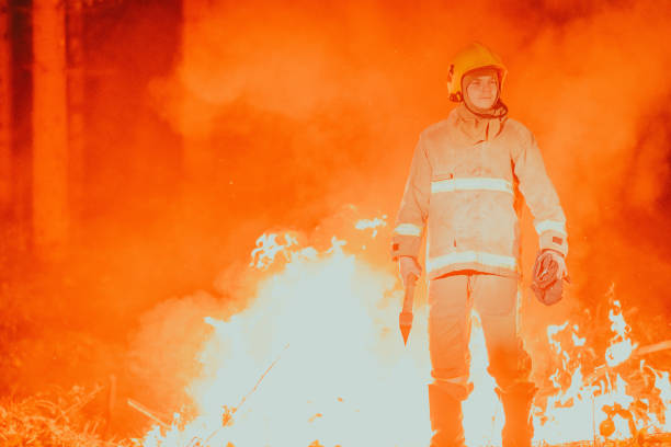 istock Firefighter at job. Firefighter in dangerous forest areas surrounded by strong fire. Concept of the work of the fire service 1472476807